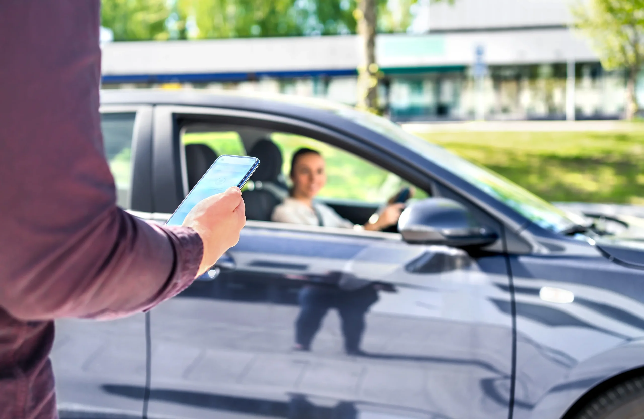 rideshare passenger looking at phone while approaching rideshare vehicle